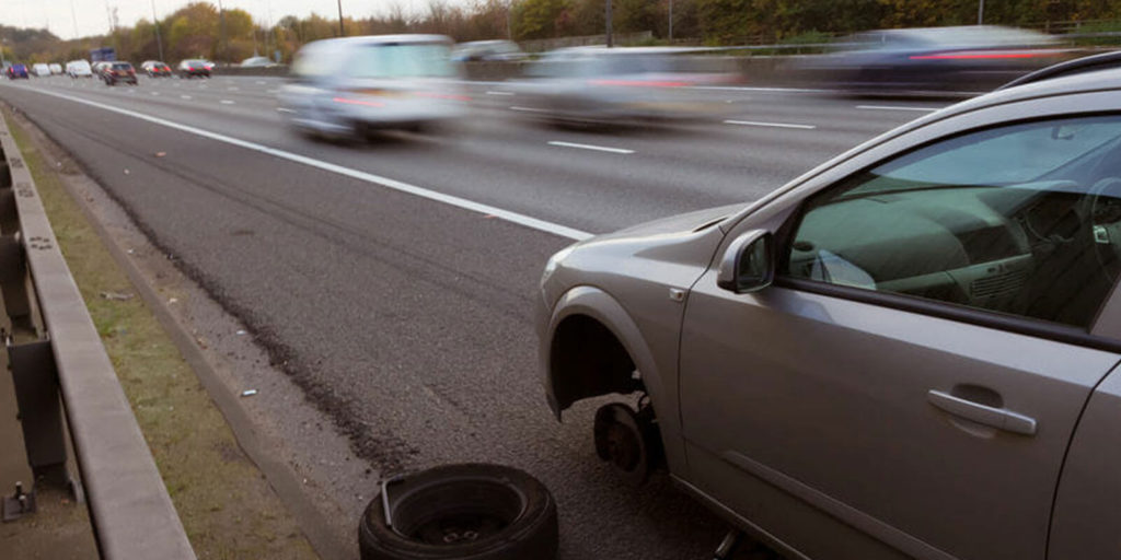 an image of a car pulled over on a hard shoulder to change a tyre 